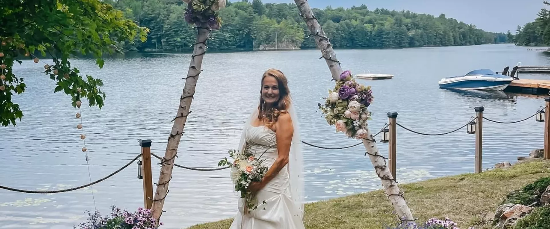 Grace Marcy Bayles, standing in front of a lake, wearing her wedding dress on her wedding day.