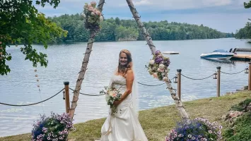 Grace Marcy Bayles, standing in front of a lake, wearing her wedding dress on her wedding day.